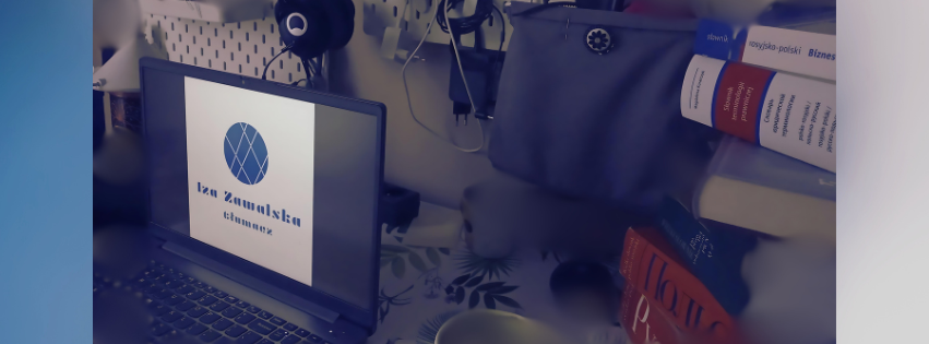 Biurko z laptopem wyświetlającym logo firmy Iza Zawalska tłumacz, w tle słowniki.